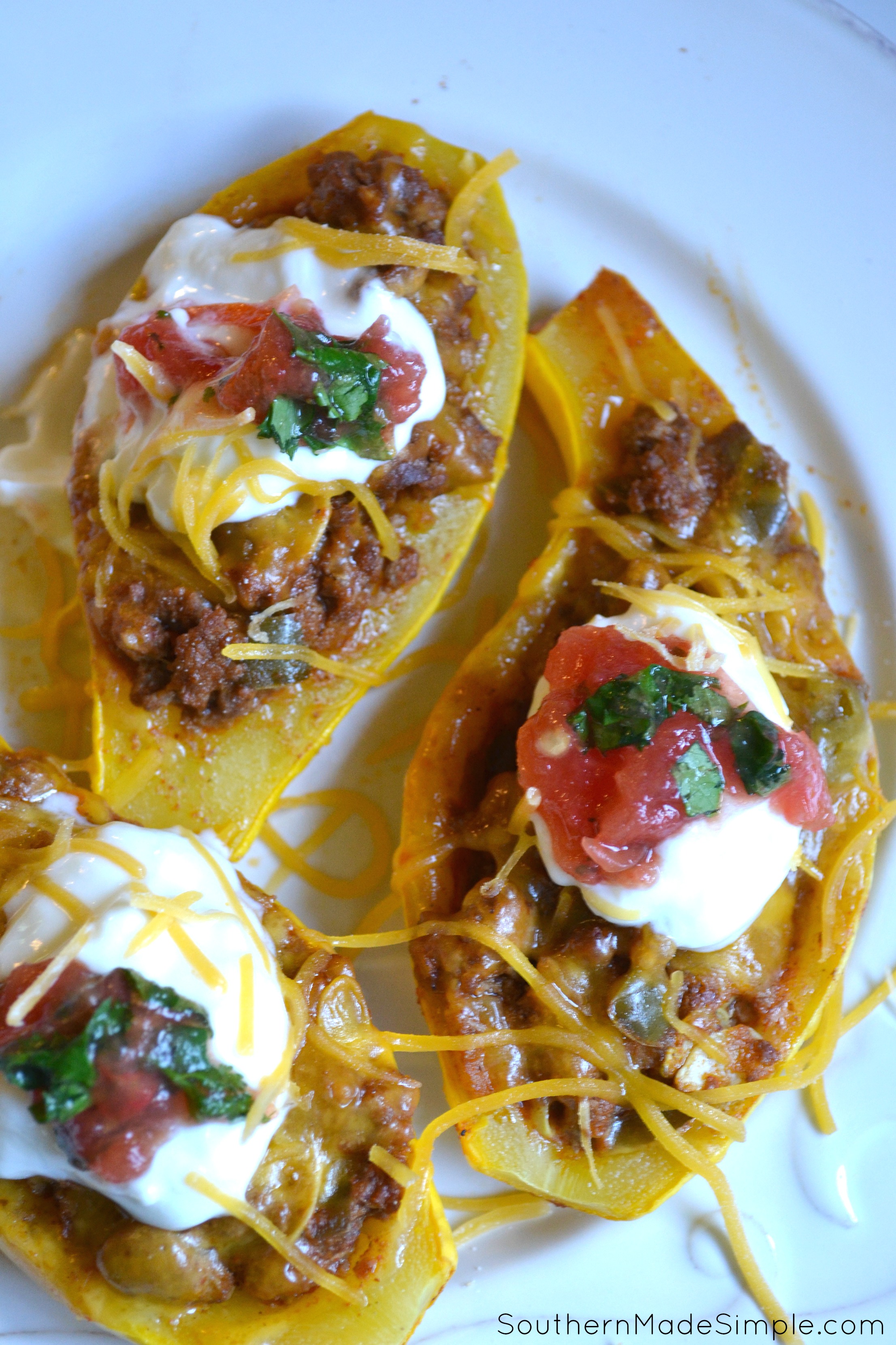 Taco Stuffed Summer Squash Boats | Fresh yellow squash halves stuffed with cheesy taco-seasoned beef, topped with sour cream, tomatoes and fresh cilantro. YUM!