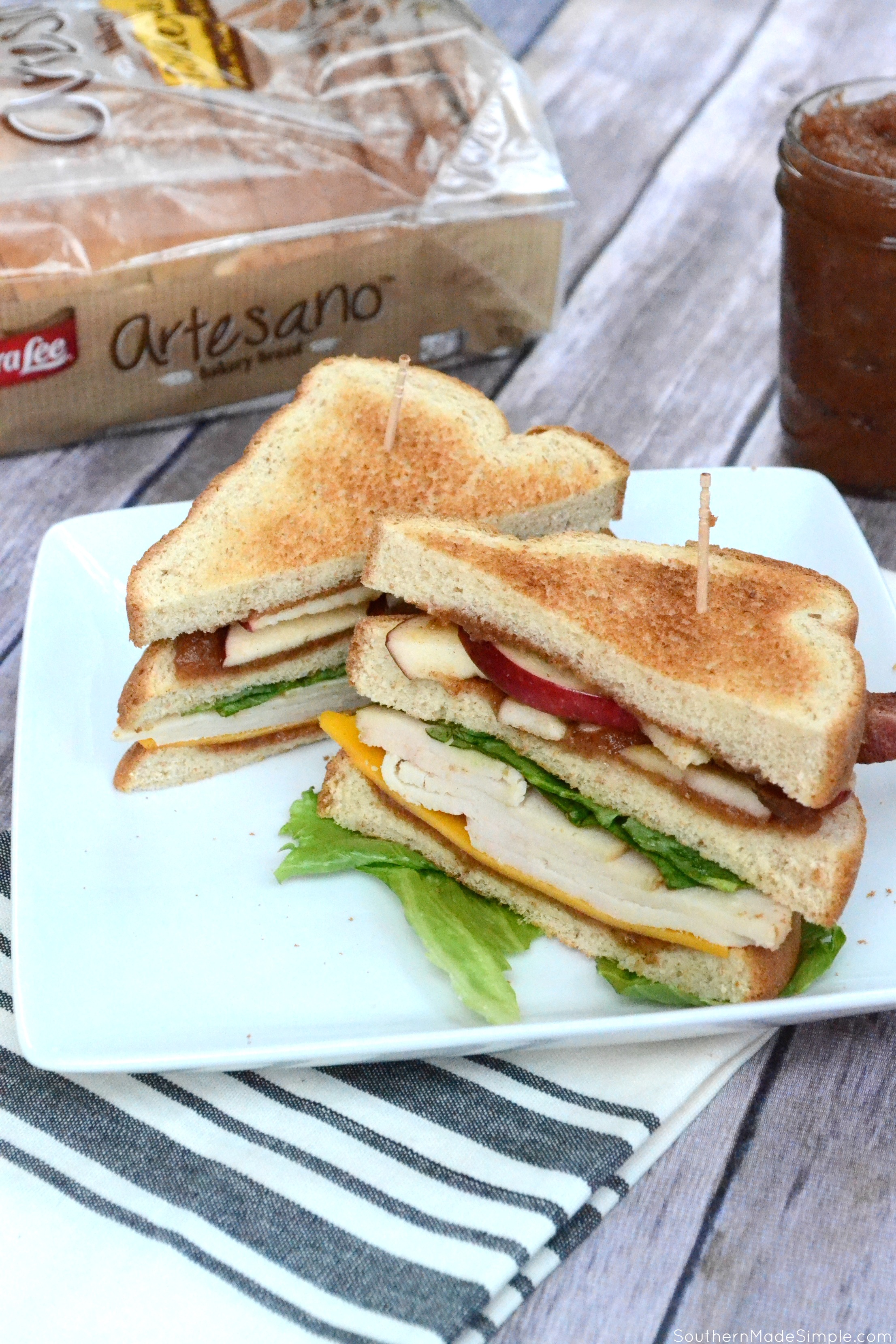 Forget what you know about turkey sandwiches. This Carved Turkey, Cheddar and Apple Butter Club Sandwich is stacked high with fresh apple slices, crispy bacon, thick carved turkey breast and the sweetest apple butter your mouth has ever tasted, and it's all nestled between three slices of Sara Lee Artesano Golden Wheat Bread! #ArtesanoGoldenWheat #Ad