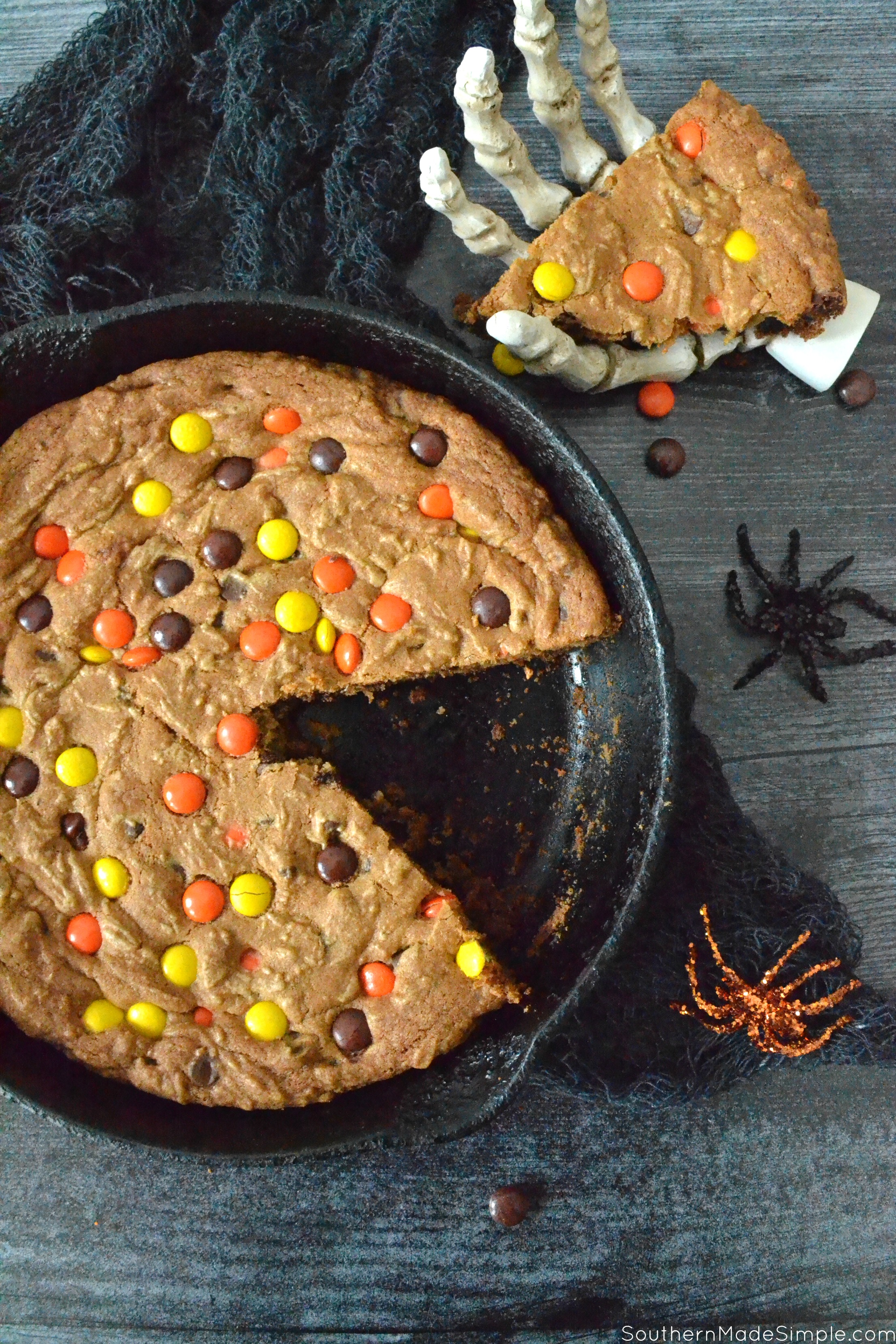 This Halloween Deep Dish Skillet Cookie is filled with chocolate chips, reese's pieces and is baked to perfection in a cast iron skillet! The only thing scary about this cookie is how GOOD it is! #halloweendessert #reesespieces #halloween